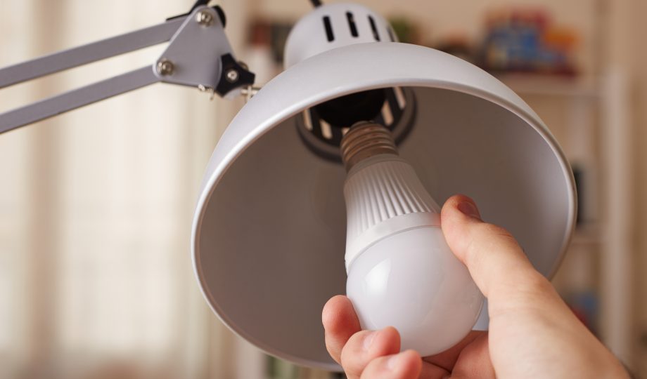 Hand changing a regular light bulb for LED