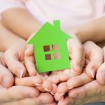Family holding green paper house in hands