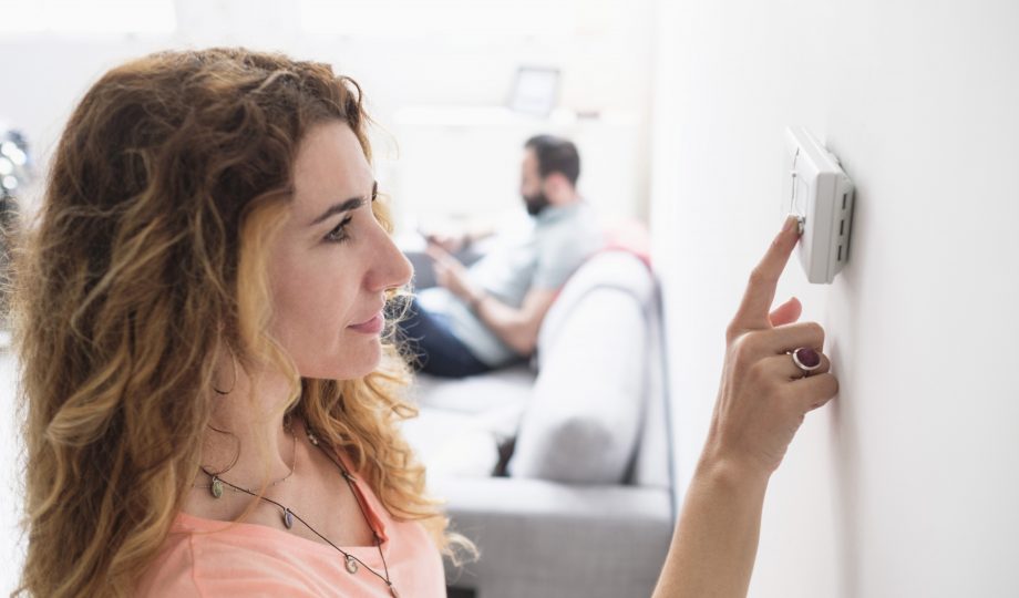 woman adjusting thermostat to save energy