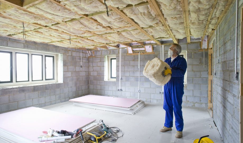 Man holding ceiling insulation in house under construction